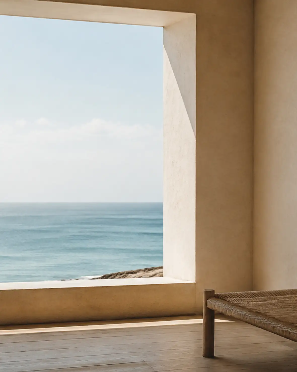 Gran ventana profunda enmarca el horizonte del Atlántico junto a un banco tejido y una pared de cal